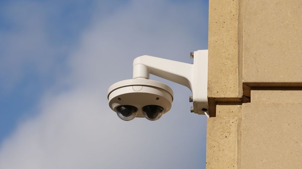 Câmera de segurança externa instalada em parede de prédio