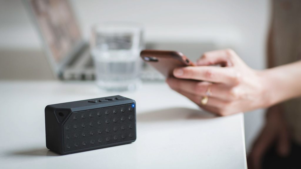 Caixa de som portátil ao lado de um celular tocando música