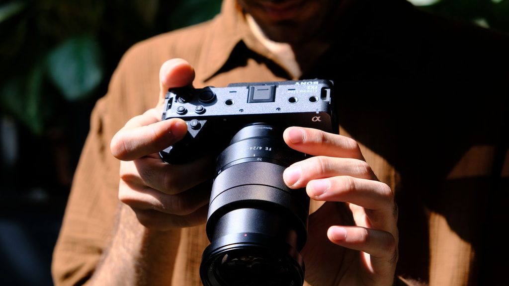 Fotógrafo segurando uma câmera mirrorless em ambiente externo