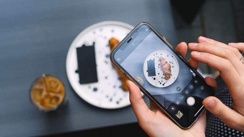 Pessoa fotografando com smartphone em ambiente externo